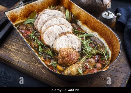 Traditioneller geschmorter Kalbsbratbraten in Scheiben mit Gemüse und Kräutern, der als Nahaufnahme in einer rustikalen Pfanne angeboten wird Stockfoto