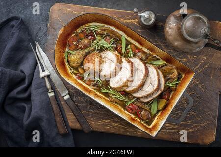 Traditionelle geschmorte Kalbsbratbraten in Scheiben geschnitten mit Gemüse und Kräutern als Draufsicht in einer rustikalen Pfanne angeboten Stockfoto