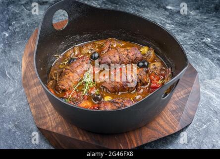 Moderne traditionelle, langsam gekochte deutsche Rinderrouladen mit Gemüse und Oliven in würziger Soße als Nahaufnahme in einem Design Stockfoto