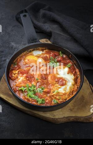 Traditionelles israelisches Nationalgericht Shakshouka, das zum Frühstück mit pochierten Eiern in Tomatensauce mit Chili und Zwiebeln angeboten wird Stockfoto