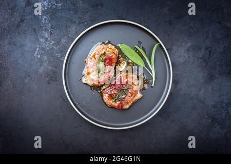 Modernes traditionelles italienisches Schweinebraten Saltimbocca alla Romana mit Parmaschinken und Salbeiblättern, die als Draufsicht in einem Nord angeboten werden Stockfoto