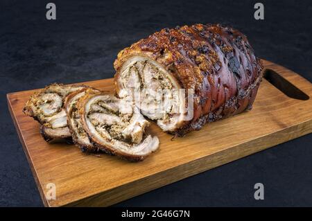 Traditionelles italienisches Schweinefleisch Porchetta arrotolata in Scheiben geschnitten und als Stück mit Kruste in Nahaufnahme auf einem modernen Holzdesign angeboten Stockfoto