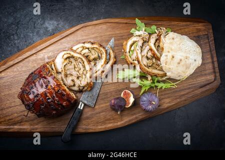 Traditionelles italienisches Schweinefleisch Porchetta arrotolata in Scheiben geschnitten und als Stück mit Pita-Brot und Feigen als Nahaufnahme auf einem modernen angeboten Stockfoto