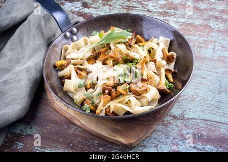 Traditionelle gebratene Tagliatelle con galletti mit Pilzen, die als Nahaufnahme in einer rustikalen Eisenpfanne angeboten werden Stockfoto