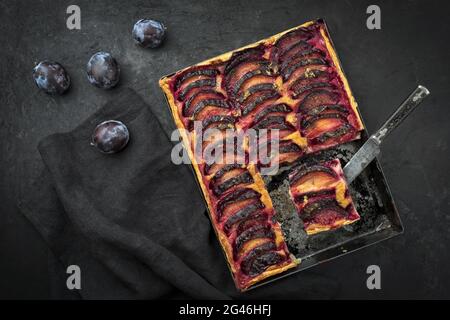 Traditionelle französische Pflaumen-Tarte mit süßen Pflaumen und Vanille, die als Draufsicht auf einem rustikalen Metalltablett angeboten werden Stockfoto