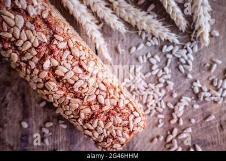 Ein Laib braunes, knuspriges Brot und ein Paket Getreide auf einem rustikalen Hintergrund mit Samen, Draufsicht, selektive Fokussierung Stockfoto