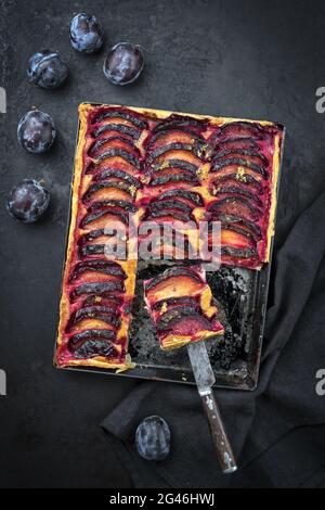 Traditionelle französische Pflaumen-Tarte mit süßen Pflaumen und Vanille, die als Draufsicht auf einem rustikalen Metalltablett angeboten werden Stockfoto