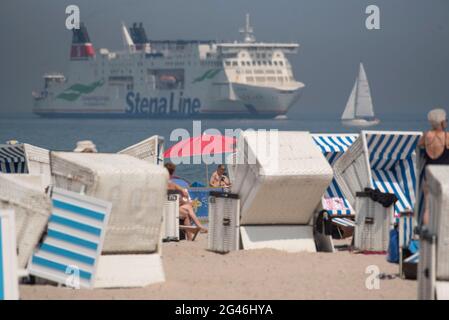 Rostock, Deutschland. Juni 2021. Ein Kreuzschiff fährt am Strand vorbei, während Urlauber bei sommerlich sonnigem Wetter am Strand sind. Am Wochenende des Jahres 19.06.20021 beginnen die Sommerferien in Mecklenburg-Vorpommern. Quelle: Frank Hormann/dpa/ZB/dpa/Alamy Live News Stockfoto