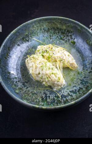 Moderner Stil traditionelle Quenelles de Brochet Fisch in Weißweinsauce Brühe in Keramik nordischen Design Schale als Nahaufnahme auf schwarz Stockfoto