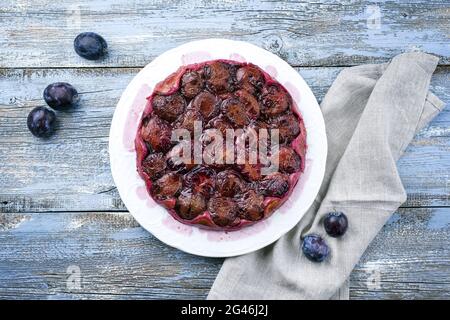 Traditionelle französische Tarte aux prunes mit süßen Pflaumen und Vanille als Draufsicht auf einem klassischen Design-Teller mit rustikalem Holz angeboten Stockfoto