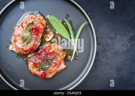 Modernes traditionelles italienisches Schweinebraten Saltimbocca alla Romana mit Parmaschinken und Salbeiblättern, die als Draufsicht in einem Nord angeboten werden Stockfoto