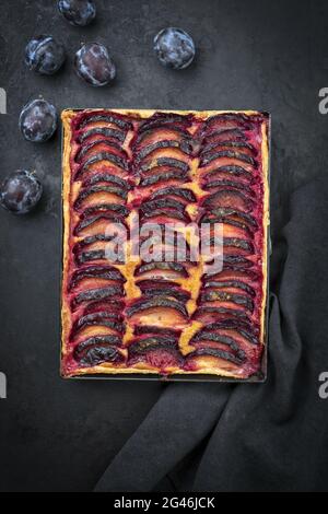 Traditionelle französische Pflaumen-Tarte mit süßen Pflaumen und Vanille, die als Draufsicht auf einem rustikalen Metalltablett angeboten werden Stockfoto