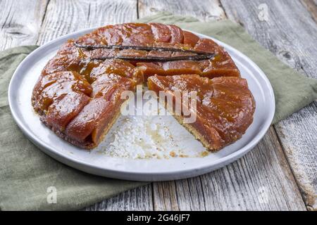 Traditionelle französische Tarte Tatin in Scheiben mit Äpfeln und Vanille, die als Nahaufnahme auf einem Teller mit modernem nordischem Design und rustikalem wo angeboten wird Stockfoto