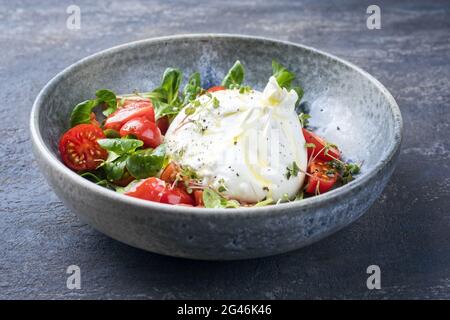 Moderner italienischer Apulien Burrata Kuhmilchkäse aus Mozzarella und Rahm, serviert mit Tomaten- und Maissalat aus nächster Nähe Stockfoto
