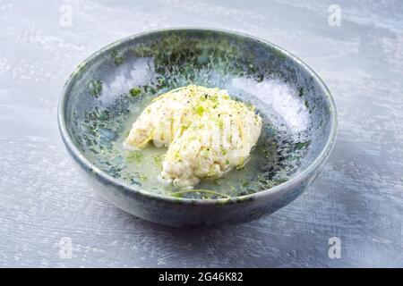 Moderne Stil traditionelle quenelles de Brochet Fisch in Weißweinsauce Brühe in Keramik nordischen Design Schüssel als Nahaufnahme auf grau r Stockfoto