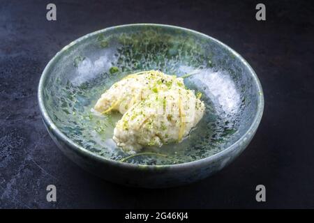 Moderner Stil traditionelle Quenelles de Brochet Fisch in Weißweinsauce Brühe in Keramik nordischen Design Schale als Nahaufnahme auf schwarz Stockfoto