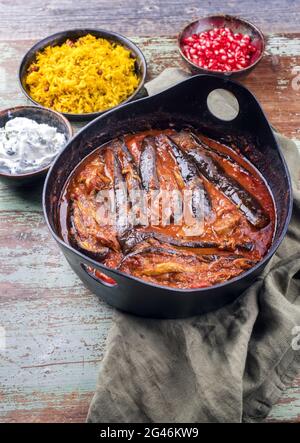 Der modern eingerichtete, langsam gekochte Eintopf aus persischem Lamm mit Auberginen, Khoresh bademjan, serviert mit Reis und Joghurt aus nächster Nähe in einem Design-Topf Stockfoto