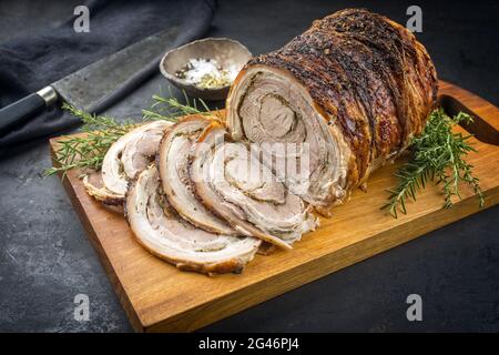 Traditionelles italienisches Schweinefleisch Porchetta arrotolata in Scheiben geschnitten und als Stück mit Kruste in Nahaufnahme auf einem modernen Holzdesign angeboten Stockfoto