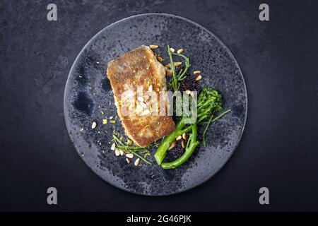 Traditionelles, in der Pfanne gebratenes Kabeljaufischfilet in Paniermehl mit Baby-Brokkoli Stockfoto