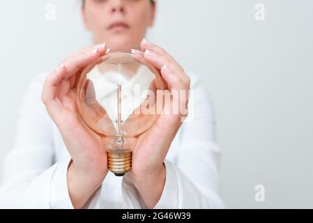 Lady Holding Lampe Mit Formellem Outfit Präsentiert Neue Ideen Für Das Projekt, Business Frau Zeigt Glühlampe Mit Zwei Händen Ausstellen Neu Stockfoto