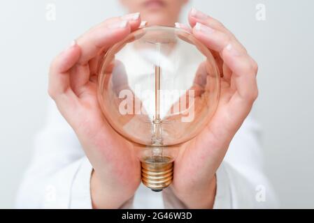 Lady Holding Lampe Mit Formellem Outfit Präsentiert Neue Ideen Für Das Projekt, Business Frau Zeigt Glühlampe Mit Zwei Händen Ausstellen Neu Stockfoto