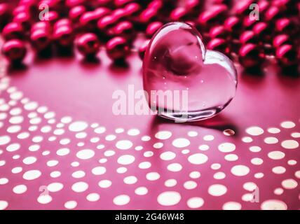 Leuchtendes transparentes Herz und eine Gruppe roter Perlen. Perfekte Valentinstag Grußkarte Hintergrund. Horizontales Bild in rosa t Stockfoto