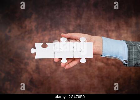 Hände Halten Zwei Stücke Puzzle.Zusammenarbeit Für Das Finden Und Lösen Von Fehlenden Ideen Bei Der Arbeit.Geschäftsmann Finden Strategie Stockfoto