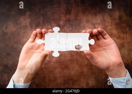 Hände Halten Zwei Stücke Puzzle.Zusammenarbeit Für Das Finden Und Lösen Von Fehlenden Ideen Bei Der Arbeit.Geschäftsmann Finden Strategie Stockfoto