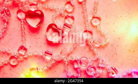 Transparente Herzen und Perlen auf Marmor in rosa Ton. Perfekte Valentinstag Grußkarte Hintergrund. Stockfoto