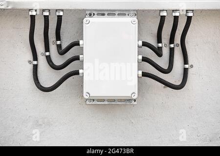 Externe elektrische Anschlussdose mit gewellten Kabelkanälen und Drähten. Professionelle Kabelisolierung. Stockfoto