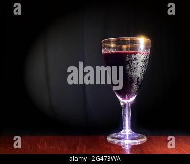 Minimalismus-Szene. Ein Glas Rotwein auf dunklem Hintergrund. Stockfoto