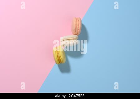 Runde mehrfarbige Macarons auf einem rosa-blauen Hintergrund mit einem Schatten. Gourmet-Dessert aus Mandelmehl Stockfoto