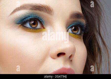 Nahaufnahme eines weiblichen menschlichen Gesichts mit gelber Innenschicht und blauen Augen-Schatten. Stockfoto