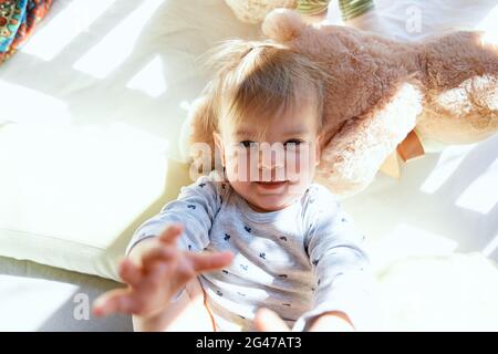 Das kleine Kind liegt in einer Holzkrippe auf einem großen Teddybären Stockfoto