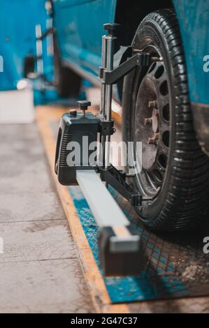 Nahaufnahme eines Reifens, der von einer Richtmaschine gespannt wird, die die automatische Ausrichtung der Räder in der Garage, Garage und den Werkzeugen für den Mechaniker passiert. Neu Stockfoto