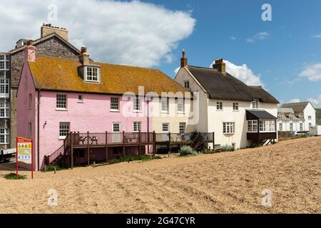 Ein rosa Häuschen in einer Reihe von malerischen Häuschen in East Beach, West Bay, Dorset, England, Großbritannien Stockfoto