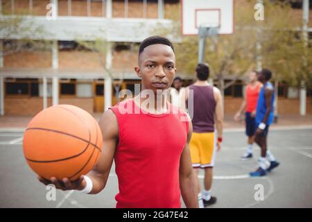 Männlicher Basketballspieler, der Basketball auf dem Basketballplatz hält Stockfoto