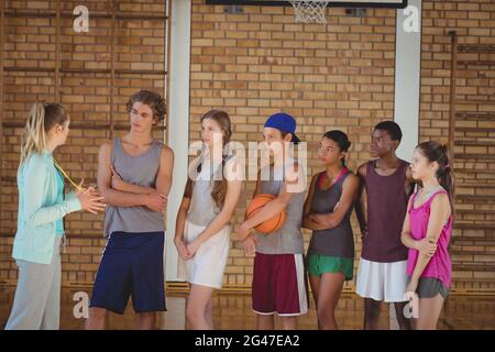 Weibliche Trainer mentoring High-School-Kids in Basketballplatz Stockfoto