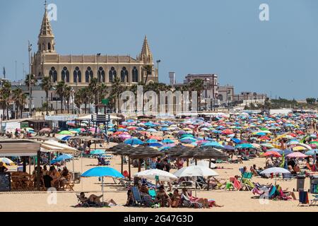 Chipiona, Cariz, Spanien - 13. Juni 2021: Der Strand von Chipiona ist voller Touristen mit Sonnenschirmen, die einen sonnigen Tag genießen Stockfoto