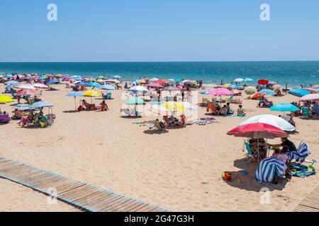 Chipiona, Cariz, Spanien - 13. Juni 2021: Der Strand von Chipiona ist voller Touristen mit Sonnenschirmen, die einen sonnigen Tag genießen Stockfoto