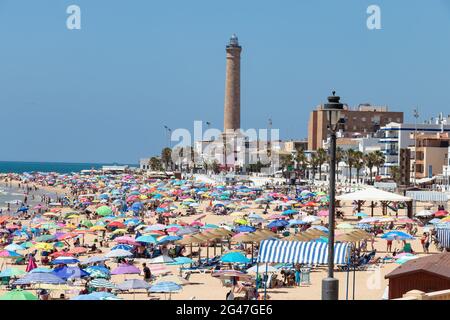 Chipiona, Cariz, Spanien - 13. Juni 2021: Der Strand von Chipiona ist voller Touristen mit Sonnenschirmen, die einen sonnigen Tag genießen Stockfoto