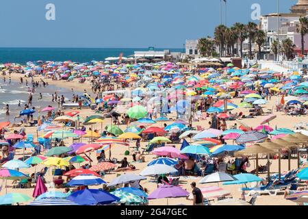 Chipiona, Cariz, Spanien - 13. Juni 2021: Der Strand von Chipiona ist voller Touristen mit Sonnenschirmen, die einen sonnigen Tag genießen Stockfoto