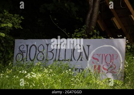 Wendover, Großbritannien. Juni 2021. Vor dem Wendover Active Resistance Camp von Stop HS2 neben der A413 ist ein bemaltes Schild zu sehen, auf dem die Kosten der Hochgeschwindigkeits-Eisenbahnverbindung HS2 kritisiert werden. Große Landflächen rund um Wendover im Chilterns AONB wurden für das Eisenbahninfrastrukturprojekt bereits von Bäumen und Vegetation freigeräumt, trotz des konzertierten Widerstands von Anwohnern und Umweltaktivisten. Kredit: Mark Kerrison/Alamy Live Nachrichten Stockfoto