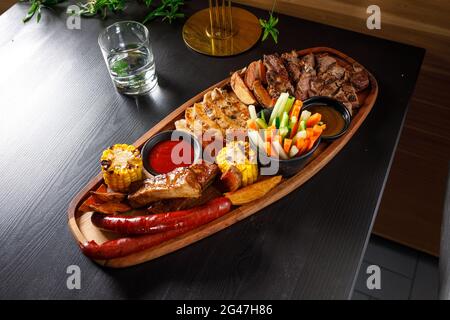Josper-Set aus Schweineribs, Hühnerfilet, Ribeye-Steak, Jagdwürsten, Mais, Kartoffeln und frisches Gemüse Stockfoto