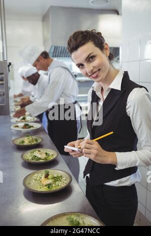 Lächelnd Kellnerin mit Notizblock in Großküchen Stockfoto