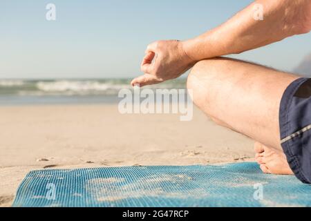 Zugeschnittenes Bild des älteren Menschen meditieren am Strand Stockfoto