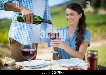 Mann gießt Rotwein in Glas von Frau gehalten Stockfoto