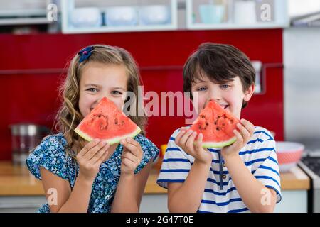 Lächelnde Geschwister mit Wassermelone in der Küche Stockfoto