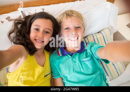 Lächelnde Geschwister machen Selfie im Schlafzimmer Stockfoto