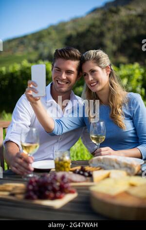 Glückliches Paar, das Selfie mit Weinläsern am Tisch macht Stockfoto